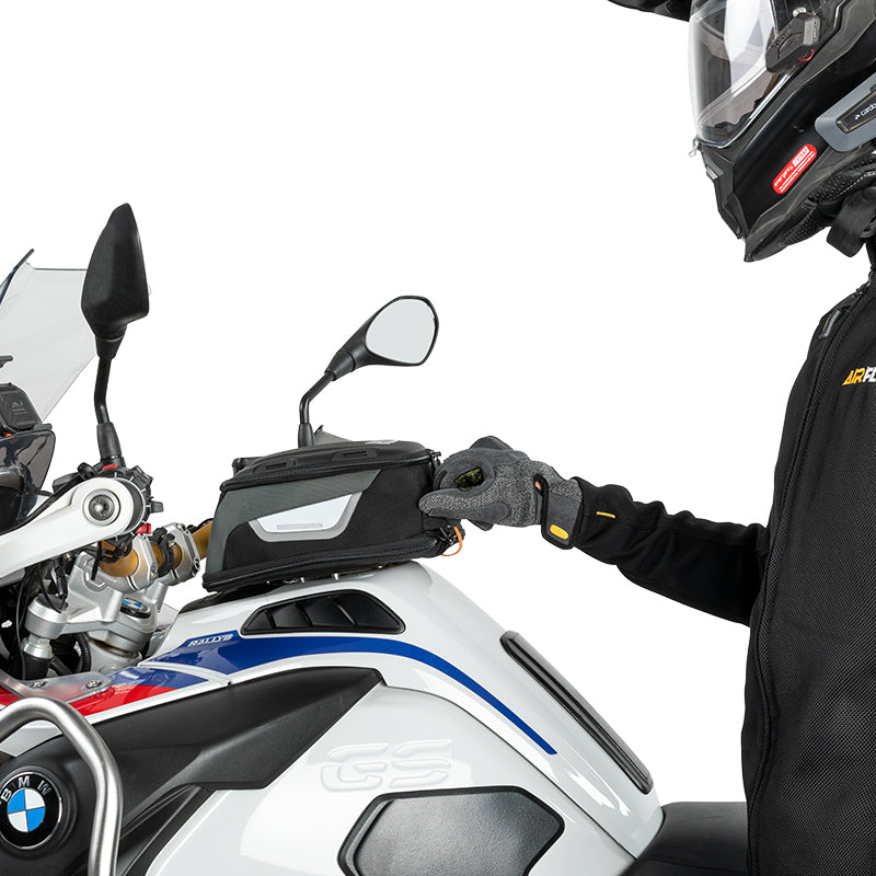 Motociclista che sgancia la borsa serbatoio dalla moto con una sola mano